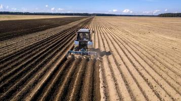 tractor - aerial view of a tractor at work - cultivating a field in spring with blue sky - agricultural machinery photo