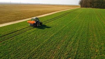 Tractor on a green field. Aerial survey photo