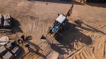 obras de transporte por carretera, reparación, colocación de una gruesa capa de asfalto, hormigón, camiones grandes, tractores, señalización vial, señales de tráfico rojas y amarillas, montones de arena, tierra, edificios antiguos, la gente hace el camino foto