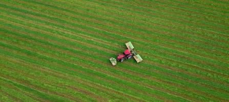 tractor mows the grass on a green field aerial view photo