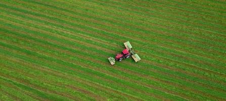 tractor mows the grass on a green field aerial view photo