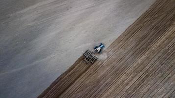 Aerial top view of a tractor, combine harvester plowing agricultural land in the spring photo