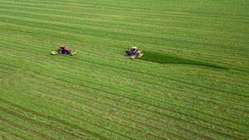 two tractors mows the grass on a green field aerial view photo