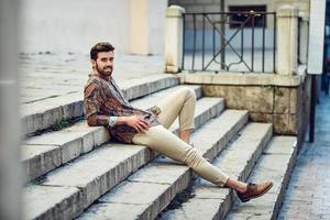 joven barbudo, modelo de moda, con camisa de fondo urbano. foto