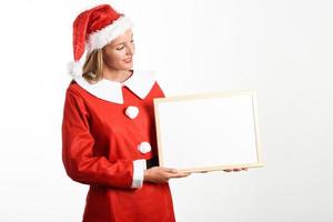 Smiling blonde woman in Santa Claus clothes with white board photo