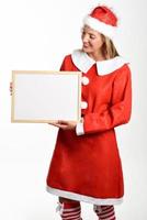 Smiling blonde woman in Santa Claus clothes with white board photo