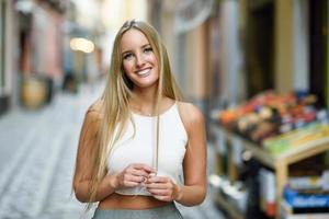 hermosa joven rubia sonriendo en el fondo urbano. foto