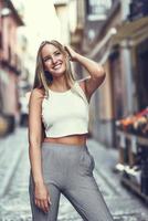 Beautiful young blonde woman smiling in urban background. photo