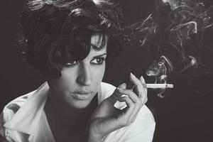 Elegant brunette woman smoking a cigarette on black background photo