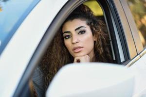 Young arabic woman inside a white car looking through the window photo