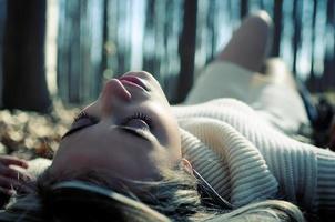 Beautiful blonde girl lying on leaves in a forest of poplars photo