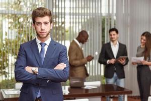 Businessman leader with arms crossed in working environment photo