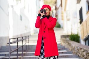 Woman taking a photograph with a reflex camera wearing red winter clothes. photo