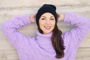 Happy young woman smiling outdoors against urban wall. photo