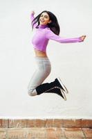 mujer persa feliz saltando al aire libre en la pared blanca foto