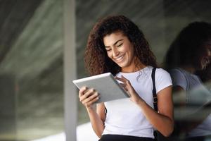 Smiling Arab girl using digital tablet in business background.