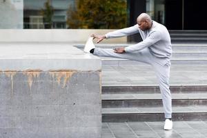 Black man doing stretching before running in urban background photo