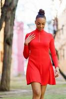 Smiling mixed woman in red dress walking down the street photo