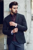 Young bearded man in urban background wearing british elegant suit in the street. photo