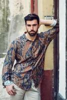 Young bearded man, model of fashion, wearing shirt in urban background. photo