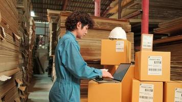 uma trabalhadora em uniforme de segurança e capacete usando scanner de código de barras para verificar pedidos de envio no armazém de encomendas, fábrica de fabricação de papel para a indústria de embalagem, serviço de transporte logístico. video