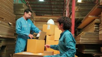 Two safety uniform workers and colleagues use a bar code scanner to check shipment orders stock at parcels warehouse, paper manufacture factory for the packing industry, logistic transport service. video