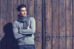 Handsome man wearing winter clothes in wooden background. photo