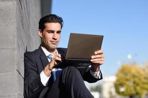 Businessman using a laptop computer sitting in the street photo