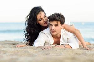 Young happy couple lying on the sand in a beautiful beach photo