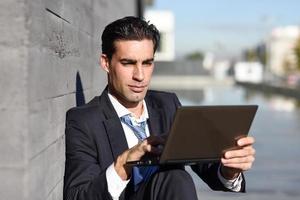 Businessman using a laptop computer sitting in the street photo