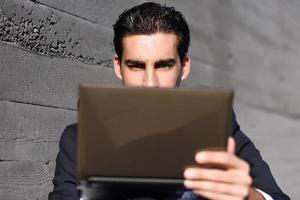 Businessman using a laptop computer sitting in the street photo