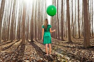 hermosa chica rubia, vestida de verde, de pie en el bosque foto