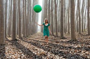 Beautiful blonde girl, dressed in green, walking into the forest photo