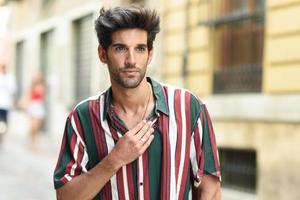 joven atractivo con cabello oscuro y peinado moderno con ropa informal al aire libre foto