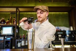 Male barkeeper squeezing lemon into cocktail in a pub photo