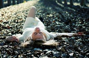 Beautiful blonde girl lying on leaves in a forest of poplars photo