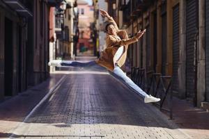 joven negro haciendo un salto acrobático en medio de la calle. foto