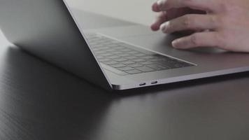 Businessman working with new modern laptop computer and eyeglasses on wooden desk in slow motion video