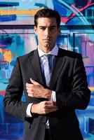 Young businessman wearing blue suit and tie in urban background photo