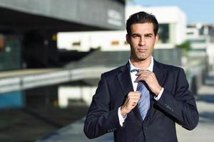 Young handsome businessman adjusting a tie in urban background photo