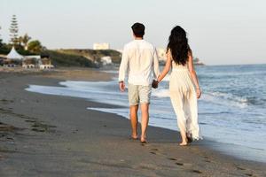 Young happy couple walking in a beautiful beach photo