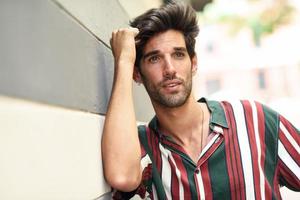 Attractive young man with dark hair and modern hairstyle wearing casual clothes outdoors photo