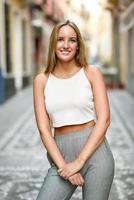 Beautiful young blonde woman smiling in urban background. photo