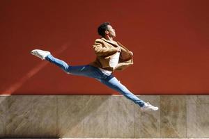 Black athletic man doing an acrobatic jump outdoors photo