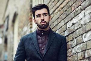 Young bearded man in urban background wearing british elegant suit in the street. photo