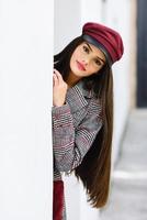 Beautiful girl with very long hair wearing winter coat and cap outdoors. photo