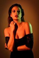 Young brunette woman in black lingerie with red and green lighting photo