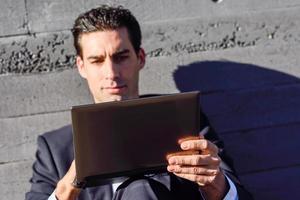 Businessman using a laptop computer sitting in the street photo