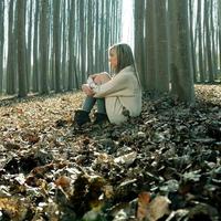 Beautiful blonde sitting on leaves in a forest of poplars photo