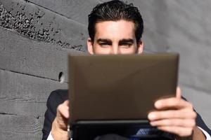 Businessman using a laptop computer sitting in the street photo